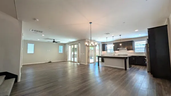 a open kitchen with a refrigerator a sink dishwasher a dining table and chairs with wooden floor