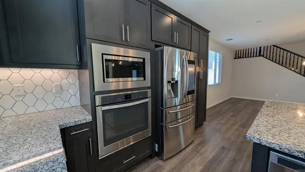 a kitchen with granite countertop cabinets stainless steel appliances and wooden floor
