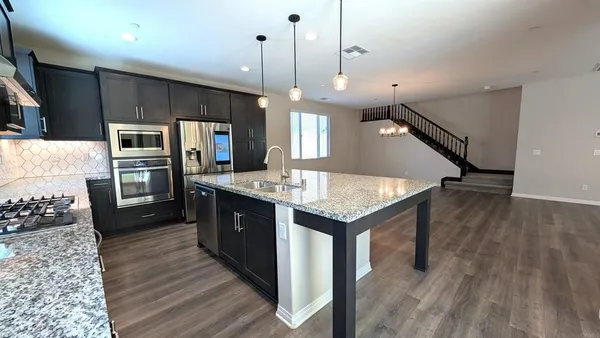 a kitchen with a refrigerator a sink and wooden floor