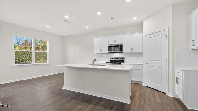a kitchen with stainless steel appliances a sink stove and wooden floor