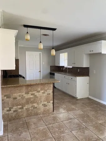 a kitchen with granite countertop a sink a stove a cabinets and a window