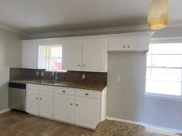 a kitchen with granite countertop a sink and a white cabinets