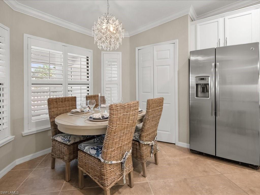 9532 Avellino Way, Unit 2726 Naples, FL 34113 - Photo 10 of 35 Dining space featuring a chandelier, crown molding, and light tile patterned floors