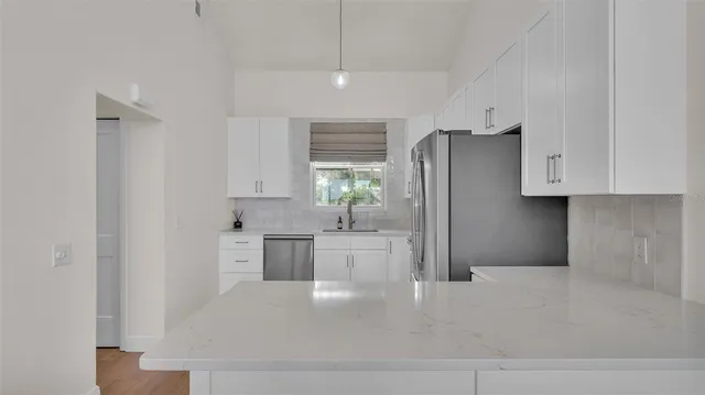 a kitchen with a refrigerator a sink dishwasher a stove and white cabinets with wooden floor