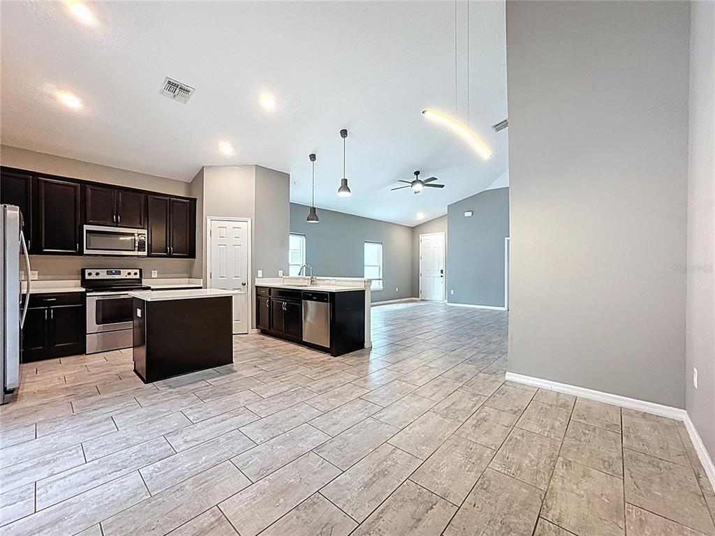 3477 Middlebrook Place Harmony, FL 34773 - Photo 24 of 78 a large kitchen with a large counter top stainless steel appliances and cabinets