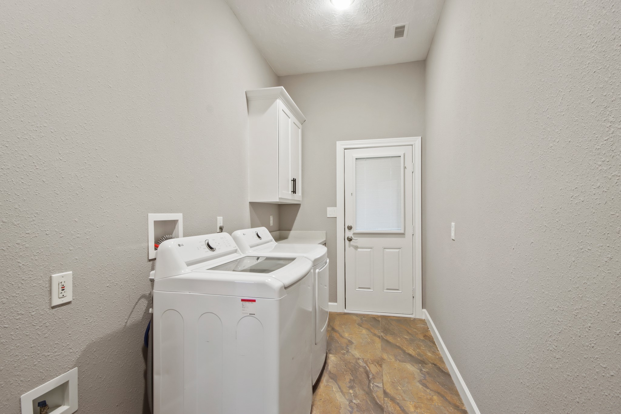 35 Susan Drive Cleveland, TX 77327 - Photo 13 of 33 This laundry room features a washer and dryer, neutral walls, tile flooring, and a door with a window, providing a functional and bright space.