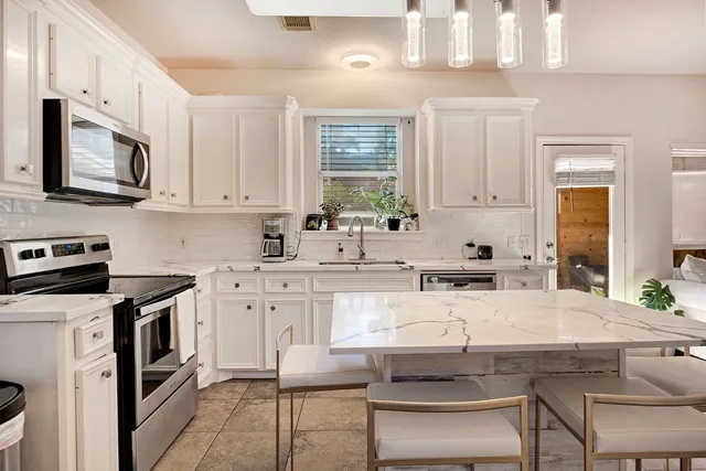 a kitchen with stainless steel appliances a stove a sink and white cabinets