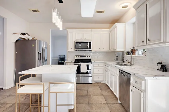 a kitchen with granite countertop a refrigerator oven a sink a stove and cabinets