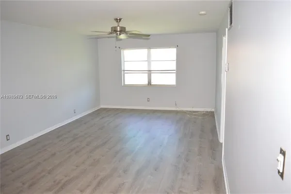 an empty room with wooden floor chandelier and windows
