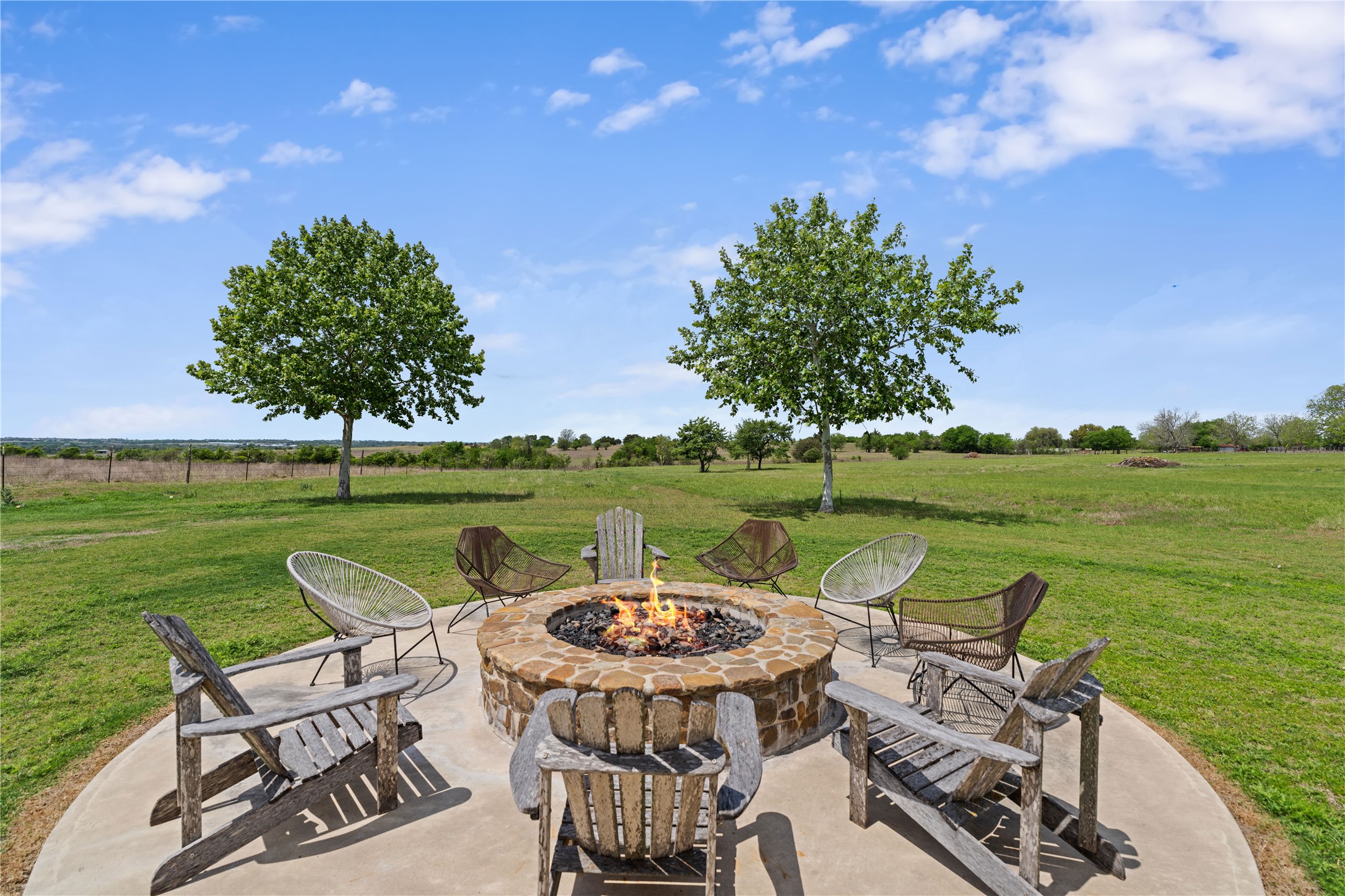 5025 Wickel Road Burton, TX 77835 - Photo 29 of 50 Views off the back of the party barn, with a stone fire pit set on a concrete patio.