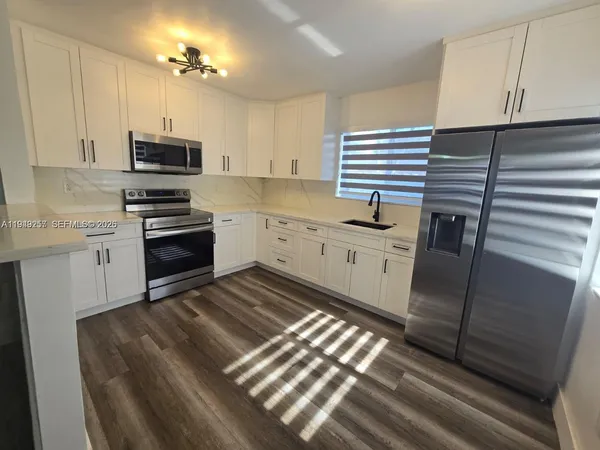a kitchen with granite countertop a sink stainless steel appliances and cabinets
