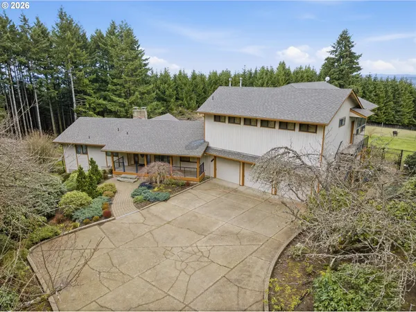 aerial view of a house with yard and trees in the background
