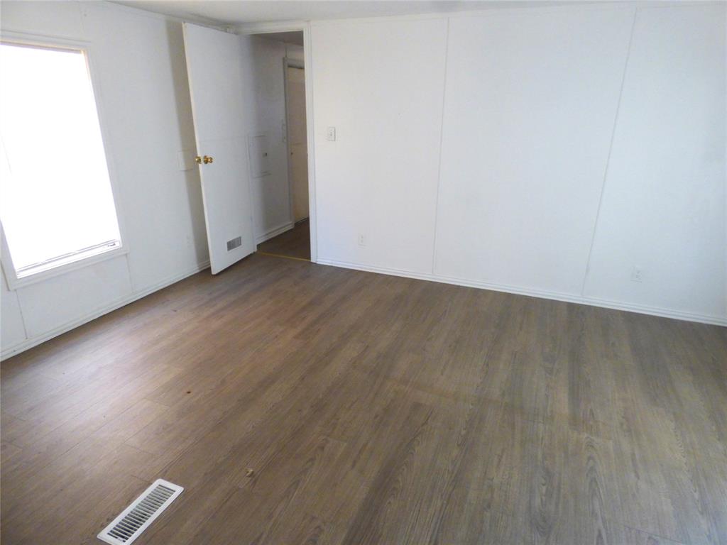 105 East 9th Street Cisco, TX 76437 - Photo 17 of 33 an empty room with wooden floor and windows