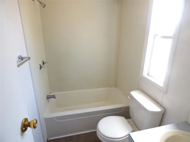 a white toilet and tub sitting next to a window