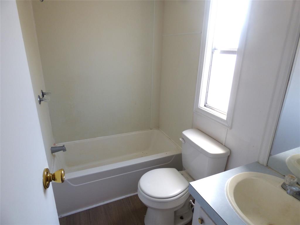 105 East 9th Street Cisco, TX 76437 - Photo 27 of 33 a white toilet and tub sitting next to a window