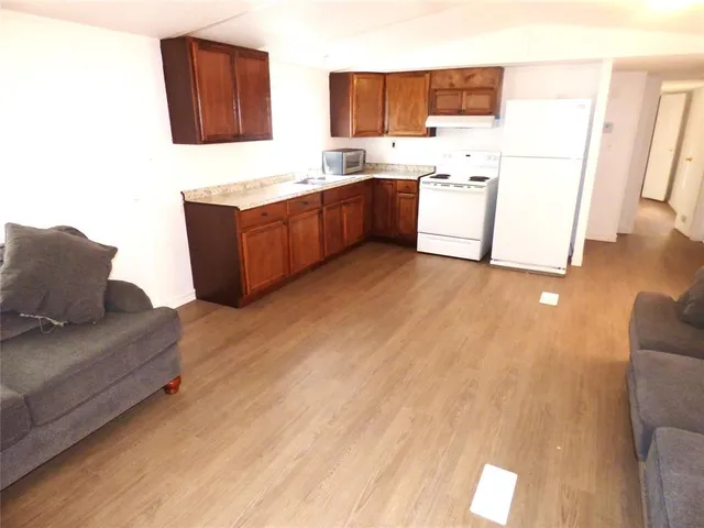 a living room with stainless steel appliances furniture and a kitchen view