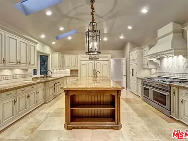 a kitchen with kitchen island granite countertop a stove and a sink