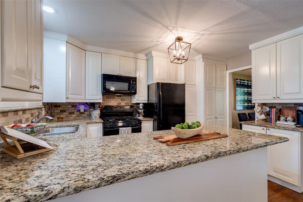 7328 Rockhurst Drive Dallas, TX 75214 - Photo 13 of 22 a kitchen with stainless steel appliances granite countertop a sink a stove top oven a refrigerator cabinets and wooden floor