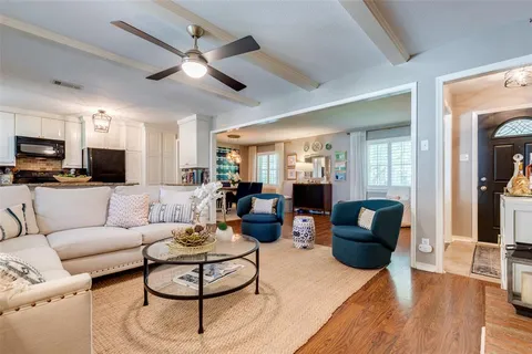 a living room with furniture kitchen view and a wooden floor