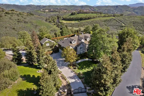 a view of house with a big yard and large trees