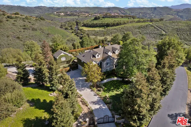 a view of house with a big yard and large trees