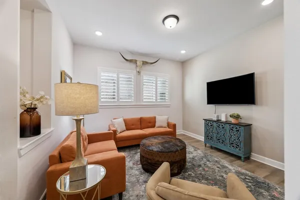 a living room with furniture a flat screen tv and wooden floor