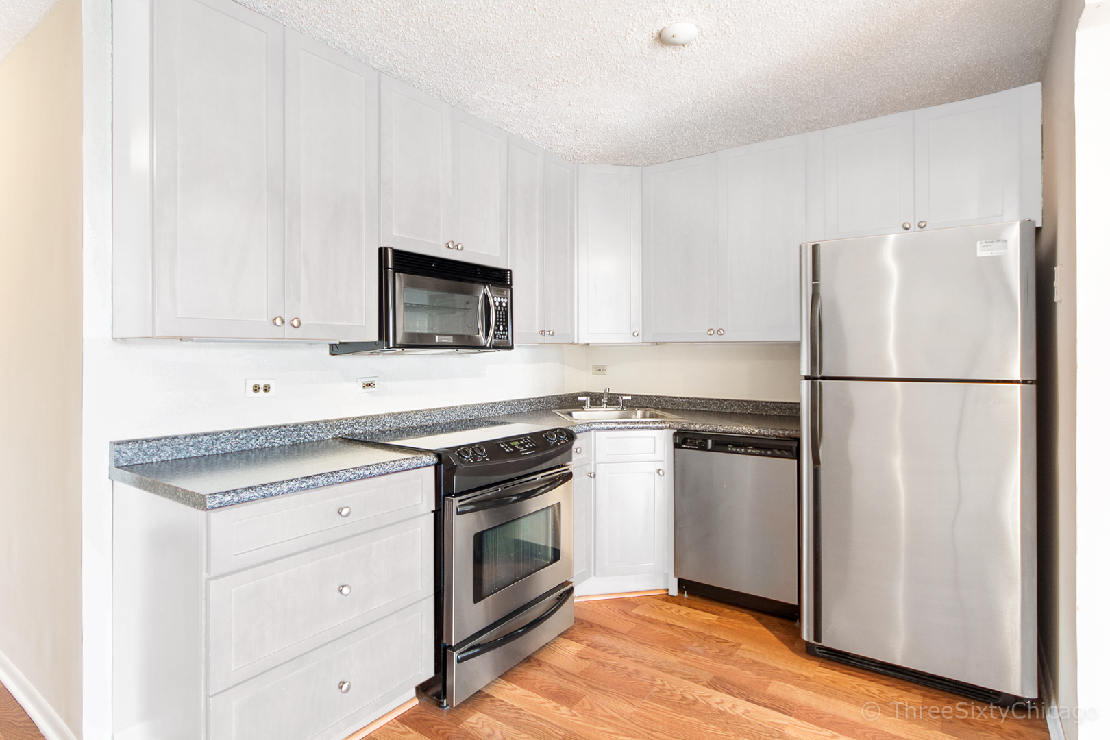 111 West Maple Street, Unit 2406 Chicago, IL 60610 - Photo 5 of 18 a kitchen with cabinets stainless steel appliances and wooden floor