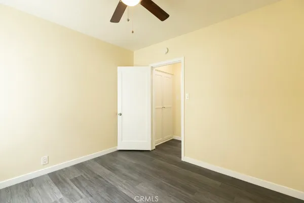 an empty room with wooden floor and ceiling fan