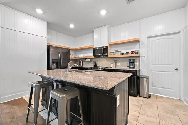a kitchen with stainless steel appliances granite countertop a sink a stove and a refrigerator