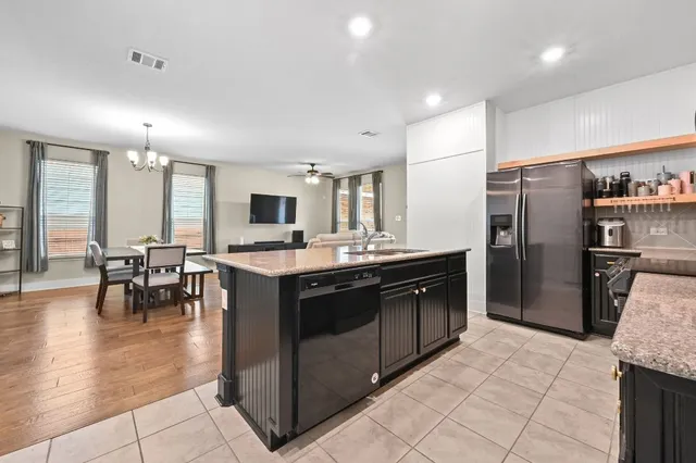 a kitchen with stainless steel appliances granite countertop a refrigerator a stove a sink a dining table and chairs