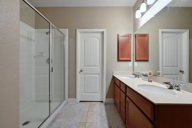 a bathroom with a double vanity sink mirror and shower