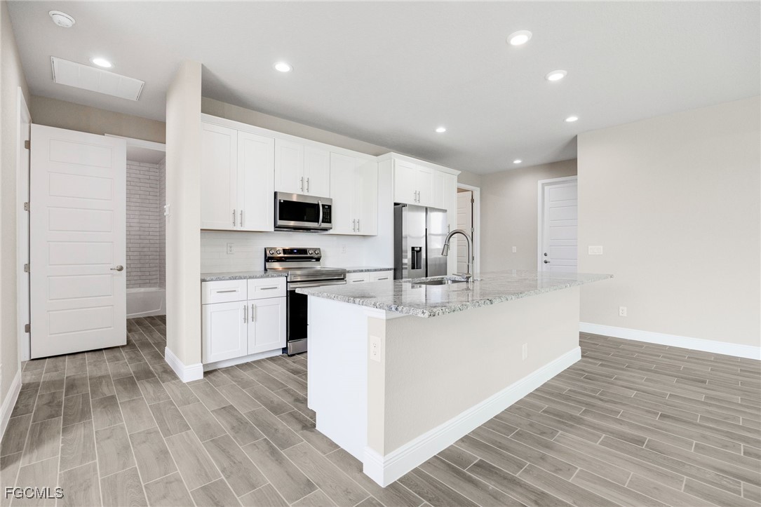 1346 Radio Loop LaBelle, FL 33935 - Photo 8 of 27 a large white kitchen with wooden floor and stainless steel appliances