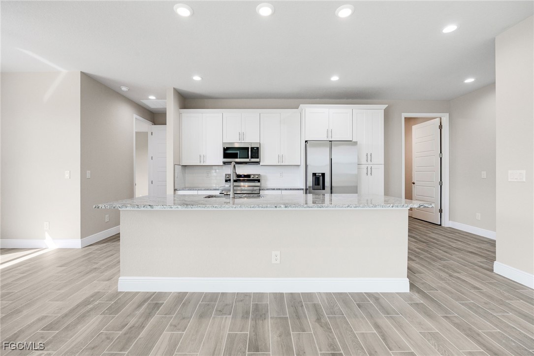 1346 Radio Loop LaBelle, FL 33935 - Photo 9 of 27 a view of kitchen with stainless steel appliances granite countertop a stove a sink a refrigerator and white cabinets with wooden floor