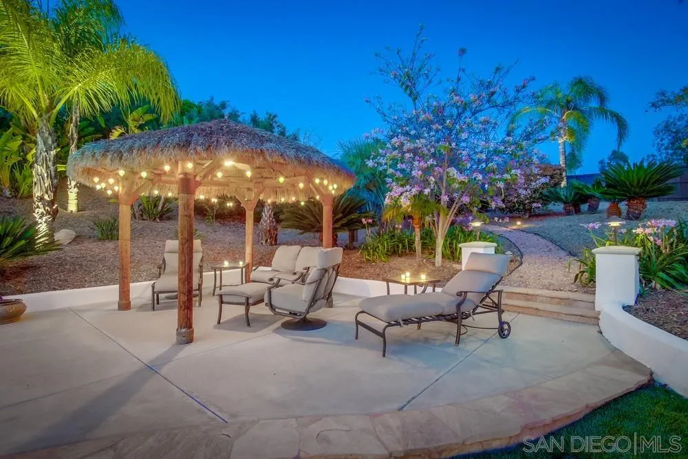 14399 Blue Sage Road Poway, CA 92064 - Photo 12 of 70 a view of a patio with couches and table and chairs under an umbrella with palm trees