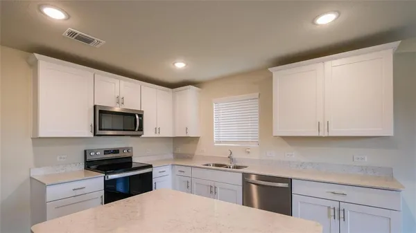 a kitchen with stainless steel appliances granite countertop a stove top oven a sink dishwasher and a refrigerator with wooden floor