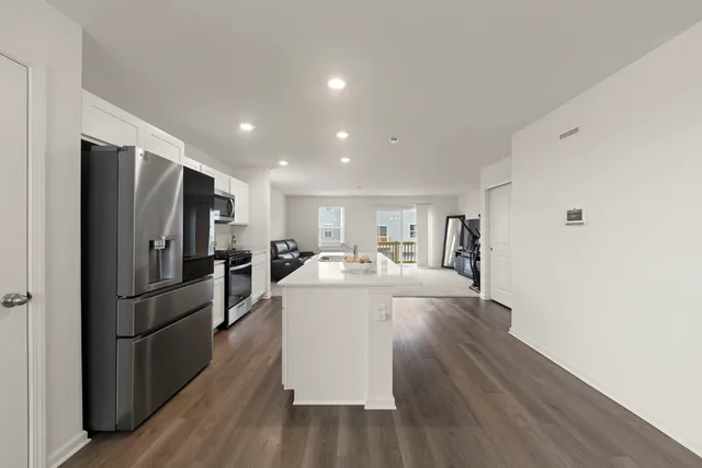 a large white kitchen with a refrigerator a stove and a wooden floor