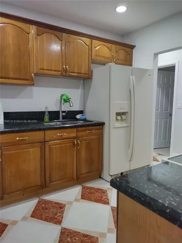 a kitchen with granite countertop a sink a stove and a refrigerator