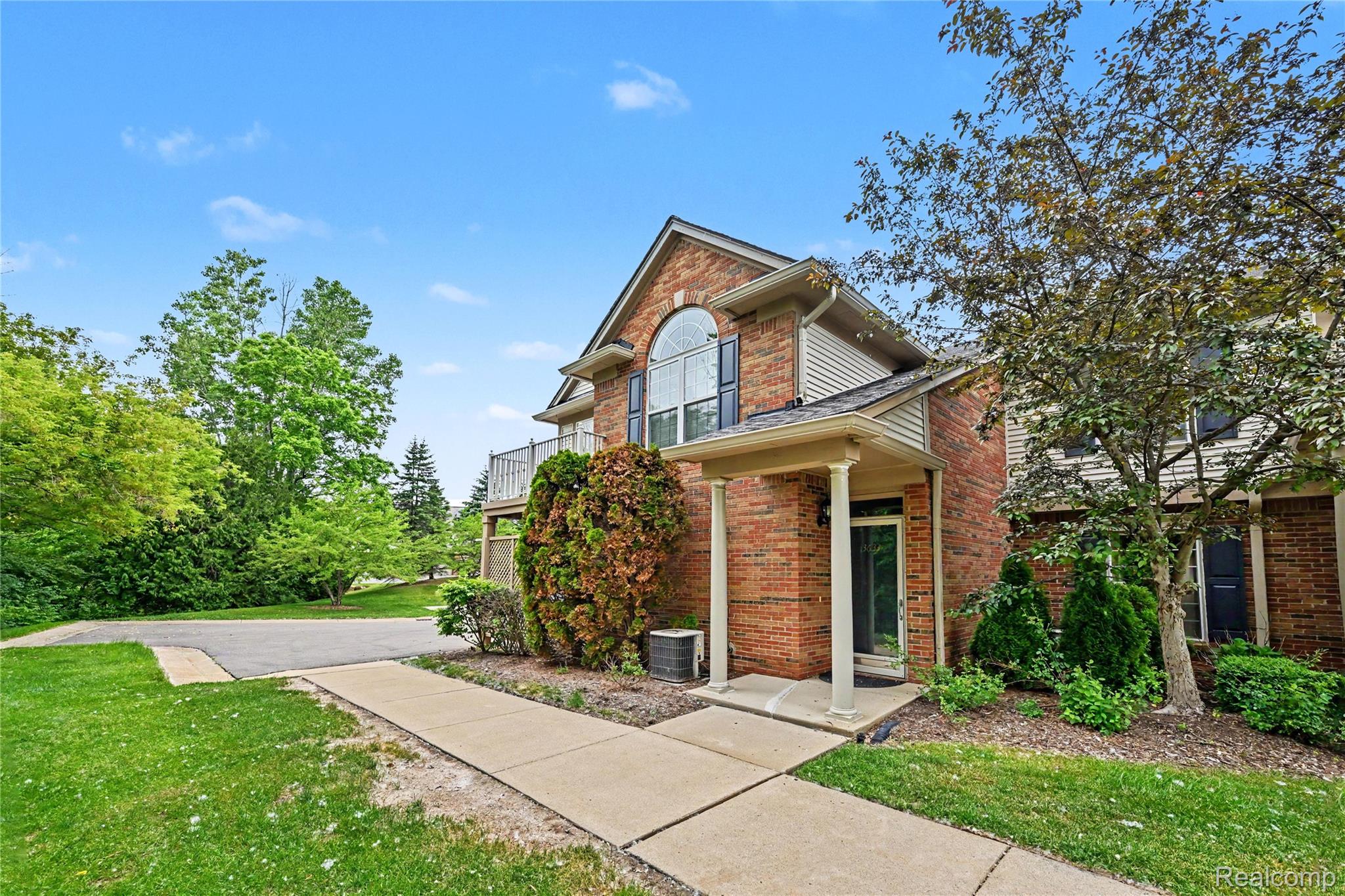 3633 Oakmonte Boulevard, Unit 189 Rochester, MI 48306 - Photo 4 of 36 Brick exterior featuring an arched window, covered entryway, and second-story balcony
