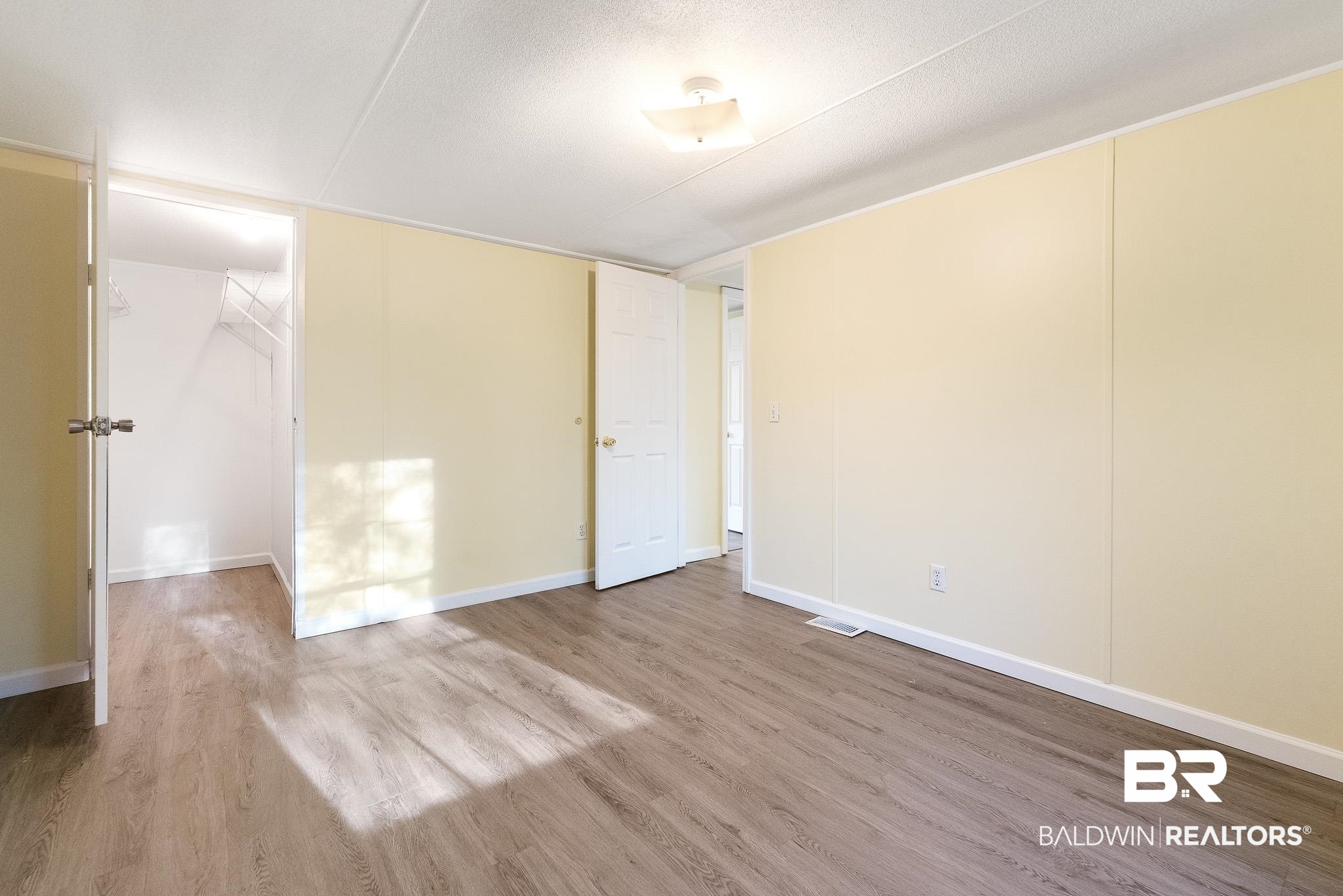 7695 Bermuda Drive Semmes, AL 36575 - Photo 23 of 27 Spare room featuring visible vents, wood finished floors, baseboards, and a textured ceiling