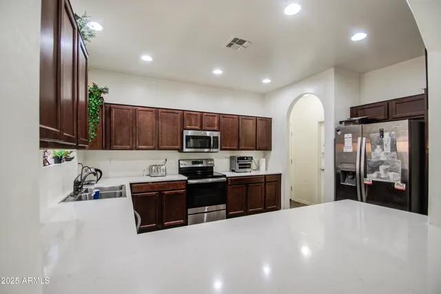 a kitchen with stainless steel appliances kitchen island granite countertop a refrigerator stove top oven and sink