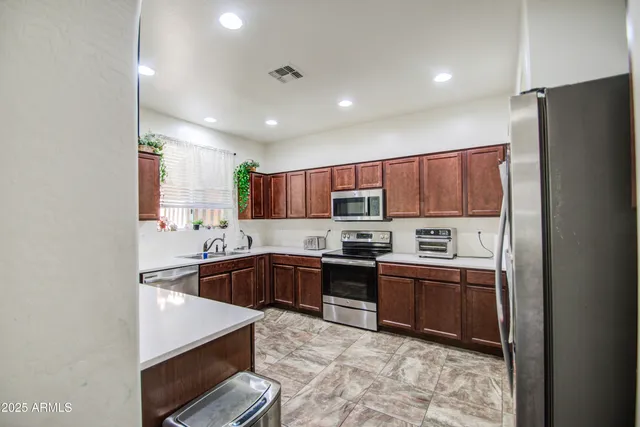 a kitchen with stainless steel appliances granite countertop a refrigerator a stove top oven a sink and dishwasher