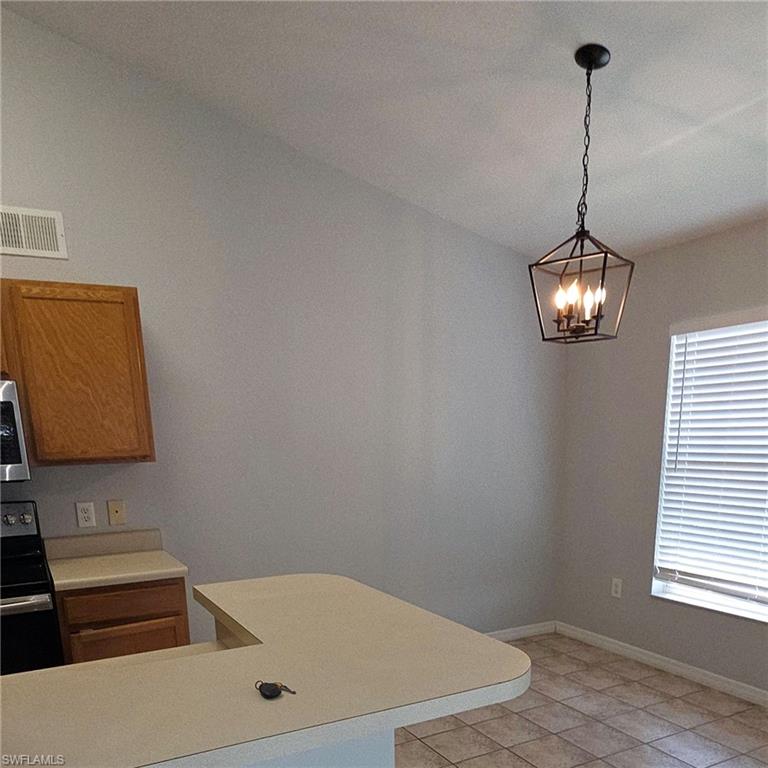7940 Preserve Circle, Unit 935 Naples, FL 34119 - Photo 6 of 7 Kitchen with light countertops, black range with electric cooktop, an office area, hanging light fixtures, and light tile patterned floors