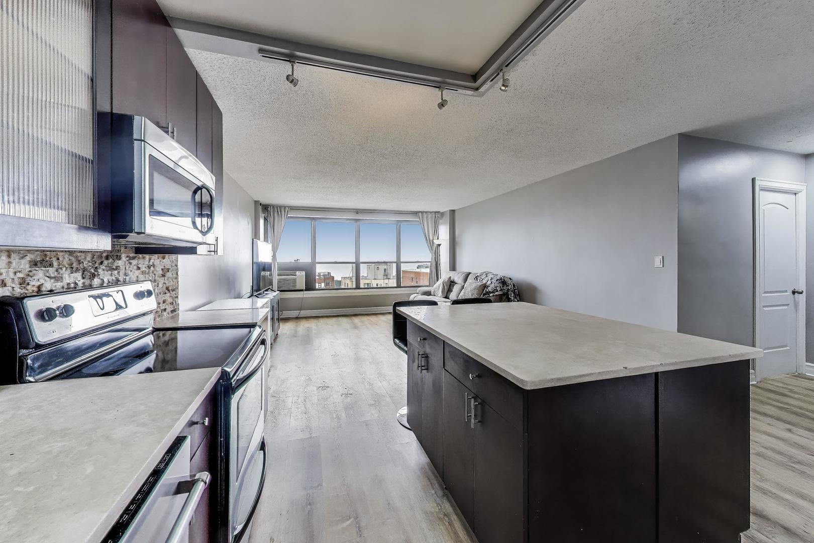 2930 North Sheridan Road, Unit 2111 Chicago, IL 60657 - Photo 11 of 31 a kitchen with kitchen island a stove a sink dishwasher and a refrigerator with wooden floor
