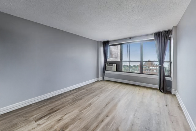 2930 North Sheridan Road, Unit 2111 Chicago, IL 60657 - Photo 13 of 31 an empty room with wooden floor and windows