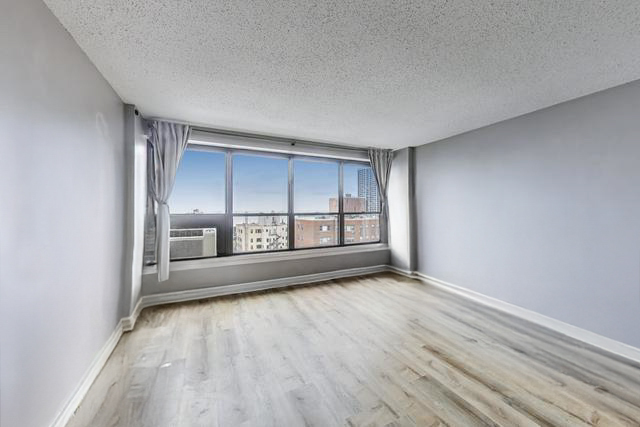 2930 North Sheridan Road, Unit 2111 Chicago, IL 60657 - Photo 3 of 31 wooden floor in an empty room with a window