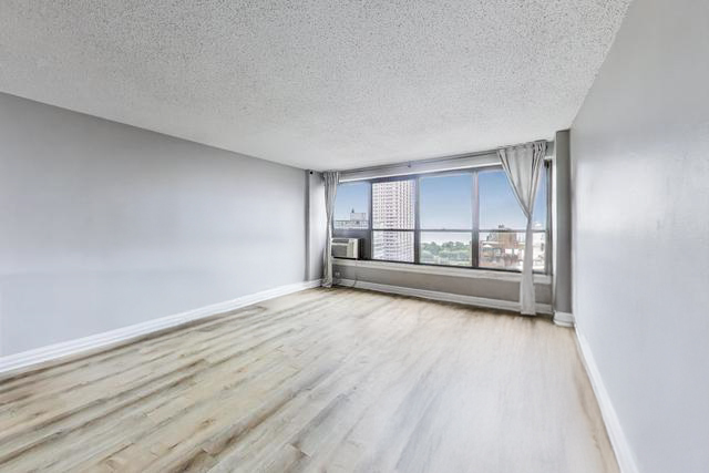 2930 North Sheridan Road, Unit 2111 Chicago, IL 60657 - Photo 5 of 31 an empty room with wooden floor and windows