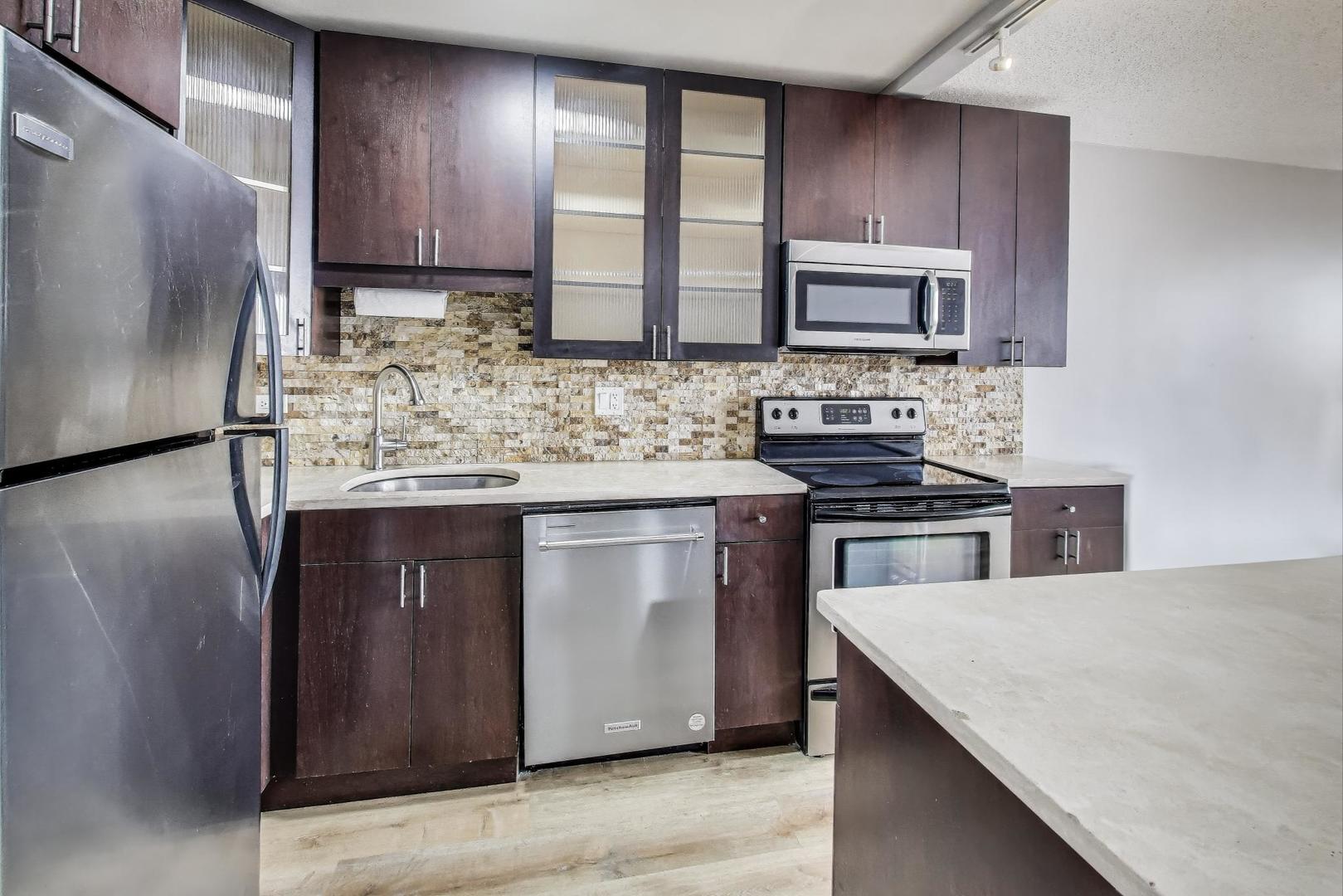 2930 North Sheridan Road, Unit 2111 Chicago, IL 60657 - Photo 10 of 31 a kitchen with stainless steel appliances granite countertop a stove a sink and a microwave