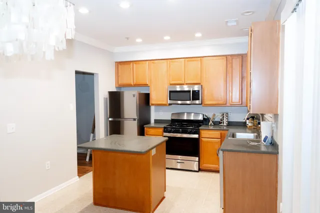 a kitchen with stainless steel appliances granite countertop a stove top oven a sink a refrigerator and white cabinets with wooden floor