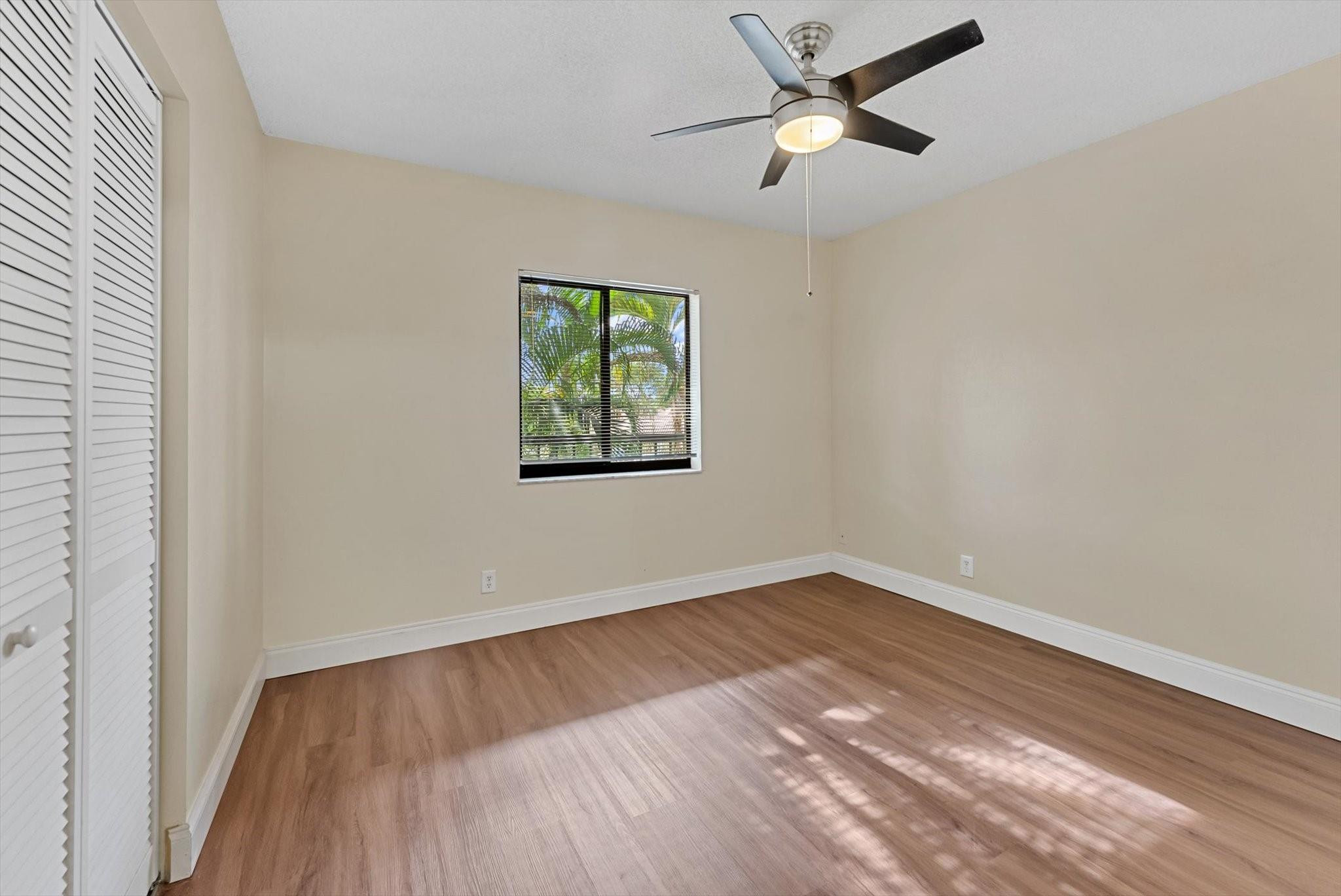 160 Northwest 70th Street, Unit 204 Boca Raton, FL 33487 - Photo 18 of 31 an empty room with wooden floor ceiling fan and windows