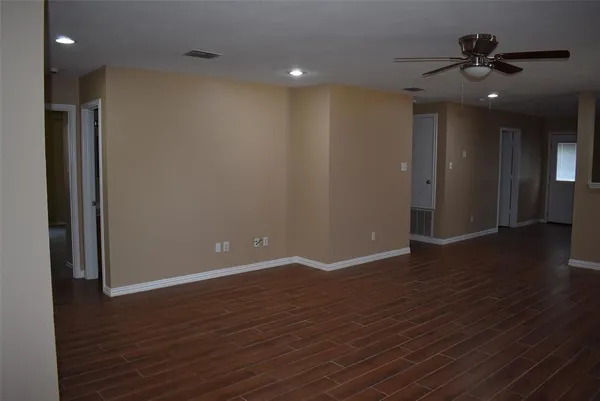 an empty room with wooden floor and a ceiling fan